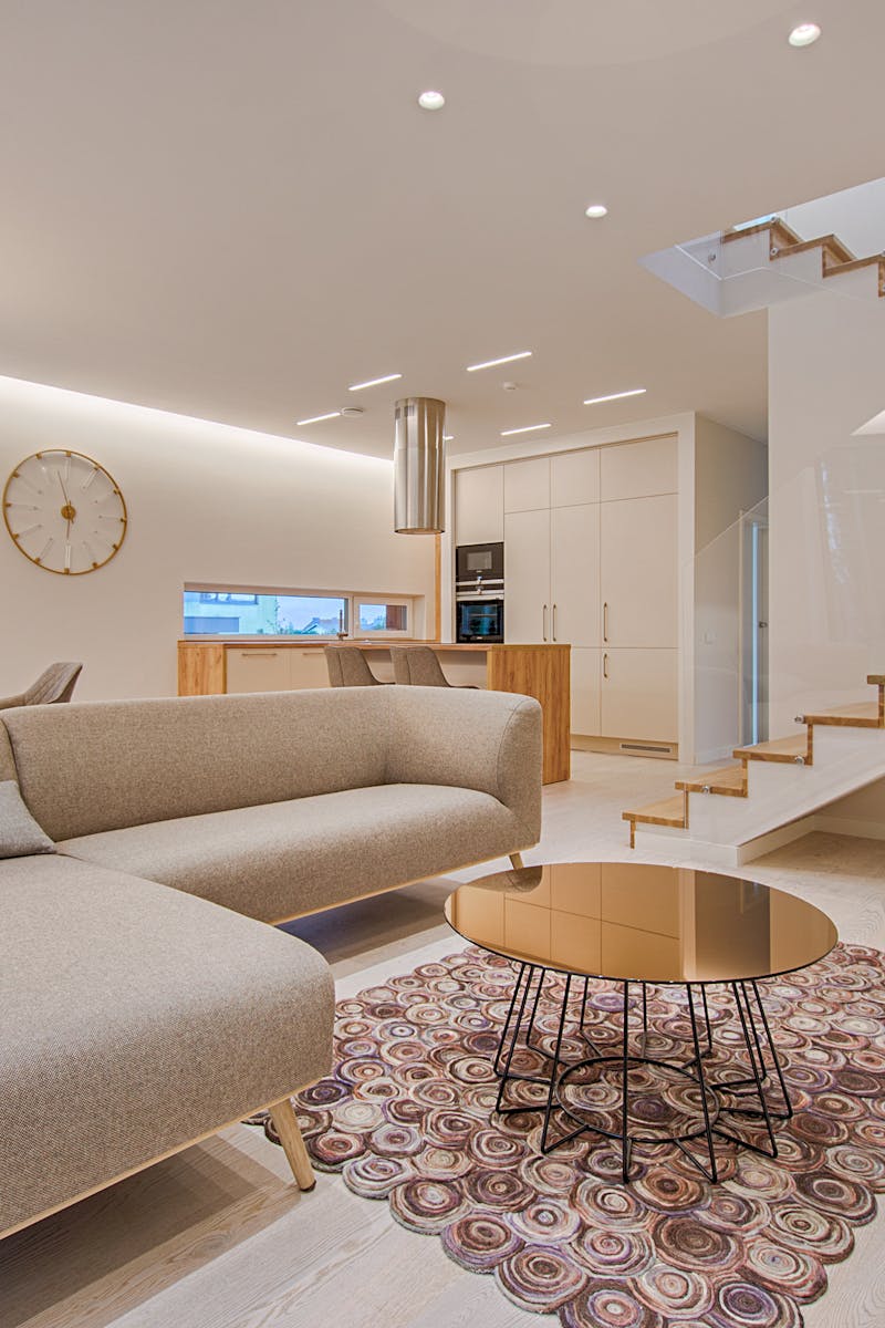 Contemporary living room with neutral tones, a sleek sofa, and elegant wooden staircase.