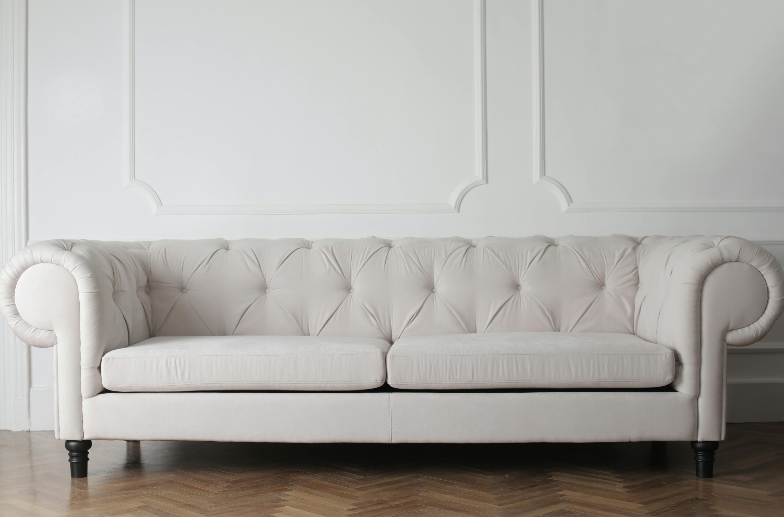 Luxurious white sofa in a modern minimalist interior with wooden flooring.